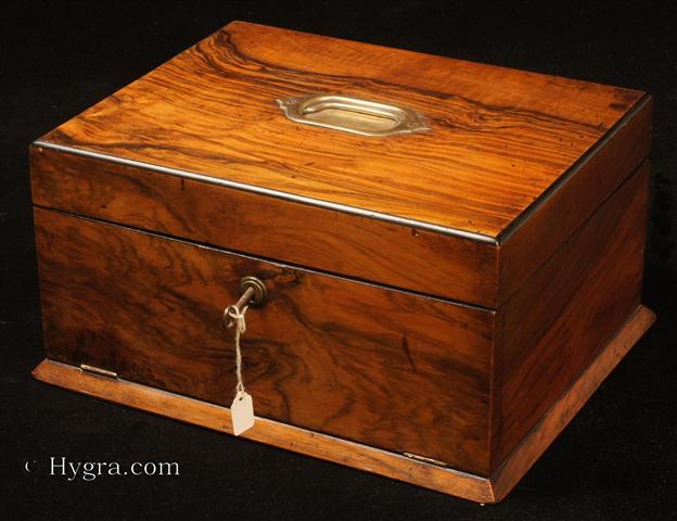 Figured walnut box with a drawer concealed behind a hinged door, opening to a fitted plush interior with lift-out tray fitted for jewelry. The box has rounded ebony edges and a countersunk carrying handle to the top. Circa 1890.  Enlarge Picture