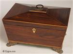 727JB: Rosewood veneered box of architectural form, fashionable in the second phase of the neoclassical period. It is cross-banded in kingwood which in turn is delineated with fine lines of contrasting woods. It stands on paw feet and its pyramid top concludes in a plaque and handle, the round plaque with a pattern suggestive of stylised flowers: daisy, sunflower, daisies. The box  has tapering shape with a gently sloping pyramid top which ends with a small flat piece adorned with a handle typical of the Regency period. Circa 1815 