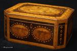 740SB: A very rare octagonal Georgian sewing box in harewood with crossbandings in various woods, ovals in burr yew, kingwood and book matched burr wood and inlays of fine leaves and dots. The top is decorated with a hand coloured print of a classical scene and framed in shaded maple, in the form of inlaid rippled ribbon. The whole orchestration of the decoration is rooted in the neoclassical tradition of the late 18th-early19th century and it is one of the finest examples of the genre. The interior contains a wealth of finely turned original sewing tools in the original tray and pieces of its two hundred year old sewing history. This box is an early example of Tunbridge ware, when the work made in the area was more in keeping with the general taste of the country and not particular to the area. There are however pointers to the work specific to the area, such as the subtle use of particularly beautiful small pieces of wood, finely turned wooden tools, the inlay of pointed leaves and dots and the painting of lines on turned pieces. The paper is also typical, although not exclusive to Tunbridge ware boxes.   Circa 1800. 