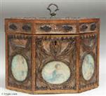 TC110: A late 18th century rolled paper tea caddy the framed panels of filigree spaced ornament on a background of mica flakes and having colored prints of classical inspiration under glass. The caddy is framed with fruitwood inlaid with a chevron of dark and light wood. Circa 1800.