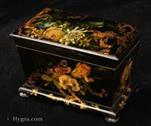 711TC: Papier mch two compartment tea caddy the japanned surface decorated with naturalistic paintings of flowers; The design is artfully orchestrated. Rococo trellised flora both frames and intersects the naturalistic  rendition of the frames and intersects the naturalistic rendition  of the the flowers and bird in a fluid cartouche. This is executed in gold leaf and provides a glamorous and exotic highlight against the subtlety  of the realistic colour of the main pictures. Circa: 1850.