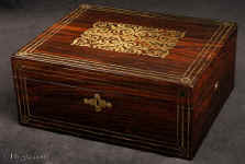 JB505:  Rosewood  box which combines style with elegance. The thick saw-cut veneers of the rosewood are selected for the rich figure of the wood which is contrasted with the brass inlay.  The design is controlled in deference to the Georgian neo-classical tradition but it also embraces the Regency influence of the Royal cabinet maker George Bullock, who introduced naturalistic elements to the earlier austere brass designs.  Circa 1825 Enlarge Picture