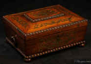 JB511: Antique box in the sarcophagus form. The box is veneered in figured rosewood and is inlaid in brass depicting stylized flora.  The fluid design of stylised flora is exceptionally fine. This is a spectacular box which encapsulates the best of the Regency era. The box stands on turned rosewood feet and has turned rosewood drop ring handles. The centre panel of the top is framed with gadrooning as is the pediment adding the architectural impact. The box has a lift out tray which has been relined . Circa1825. Enlarge Picture
