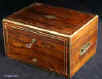 JB410: Early 19th century box veneered with exceptionally beautifully figured rosewood. The box is edged in rounded brass and further enhanced with two lines of brass stringing. It has brass handles to the sides. There is a lower drawer with a separate lock to the front. This is divided in three compartments. The top part of the box has a lift-out tray and a flap-down envelope compartment. Both retain the original lining of green leather and velvet. The maker's label is visible stuck on the inside of the flap. The lower inside of the box is also covered in the original leather. Small veneer cracks to the top. The box has two working locks and one key which opens both locks. Circa 1820. Enlarge Picture