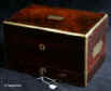 JB413: Antique George the fourth period box veneered in rosewood and edged in rounded brass for strength and contrast with the dark wood. It also has flat brass carrying handles on both sides. It has a lower jewellery drawer with a separate working lock and key which retains its original leather cover and velvet lining with a ring compartment. The top part of the box has been fitted with an extra lift-out tray. The box has two working locks and keys. Circa 1830. Enlarge Picture
