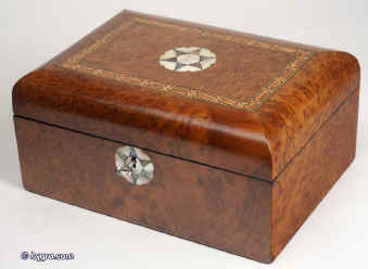 JB307: Antique, late 19th c. box, with the top curved veneered with amboyna, and inlaid with parquetry, and having an escutcheon and central inlay to the top depicting a compass point star in contrasting mother of pearl and abalone. Inside, the box has a replacement liftout tray lined with velvet and suitable for jewelry and knickknacks.  Circa 1890. Enlarge Picture