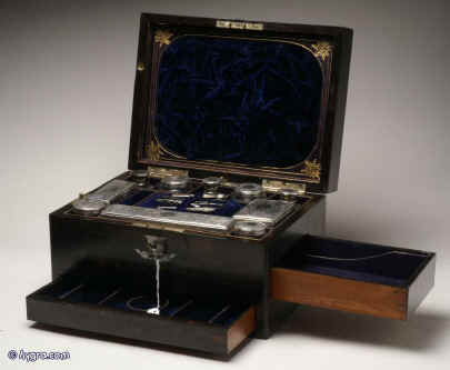 JB319: A fully fitted and intricate dressing box  by C. Henry of Manchester in figured coromandel inlaid with engraved shield to the top and escutcheon  in mother of pearl opening to a compartmentalized interior and retaining its original chased silver toped cut  lead crystal jars and bottles by Thomas Whitehouse and having two sprung drawers fitted for jewelry. There is a liftout mirror with gold embossed mirror in the lid and a blind embossed leather document wallet behind. Circa 1860. Enlarge Picture
