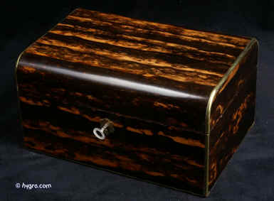 JB415: Rounded top Victorian box veneered in strongly figured coromandel striated with warm light ripples of lighter colour. The structure is strengthened and enhanced with rounded brass. The original interior retains its original leather-covered tray and purple lining. There is a circular watch compartment and long ring slot. The box has a working lock and key. Circa 1860. Enlarge Picture