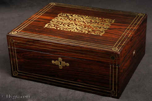 JB505:  Rosewood  box which combines style with elegance. The thick saw-cut veneers of the rosewood are selected for the rich figure of the wood which is contrasted with the brass inlay.The design is controlled in deference to the Georgian neo-classical tradition but it also embraces the Regency influence of the Royal cabinet maker George Bullock, who introduced naturalistic elements to the earlier austere brass designs. Circa 1825 Enlarge Picture