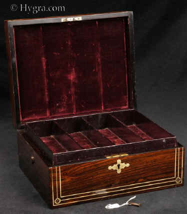 JB505:  Rosewood  box which combines style with elegance. The thick saw-cut veneers of the rosewood are selected for the rich figure of the wood which is contrasted with the brass inlay.The design is controlled in deference to the Georgian neo-classical tradition but it also embraces the Regency influence of the Royal cabinet maker George Bullock, who introduced naturalistic elements to the earlier austere brass designs. Circa 1825 Enlarge Picture