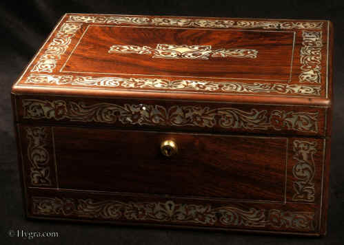 JB 514: Antique figured rosewood box with rounded edges, inlaid to the top and front with fine inlays of mother of pearl and white metal depicting stylized curved foliage, the box having a liftout tray, a separately locked lidded drawer fitted for jewelry, and in the lid a document wallet with gold tooling and velvet. The box is labeled by Thomas Woolfield, Manufacturer, No. 71 & 72, CHURCH STREET LIVERPOOL. Inside the box retains its original embossed leather silk and velvet linings. New detachable velvet pads have been made for the compartmentalized lift out tray. Circa 1835  Enlarge Picture