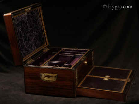 JB 514: Antique figured rosewood box with rounded edges, inlaid to the top and front with fine inlays of mother of pearl and white metal depicting stylized curved foliage, the box having a liftout tray, a separately locked lidded drawer fitted for jewelry, and in the lid a document wallet with gold tooling and velvet. The box is labeled by Thomas Woolfield, Manufacturer, No. 71 & 72, CHURCH STREET LIVERPOOL. Inside the box retains its original embossed leather silk and velvet linings. New detachable velvet pads have been made for the compartmentalized lift out tray. Circa 1835 Enlarge Picture