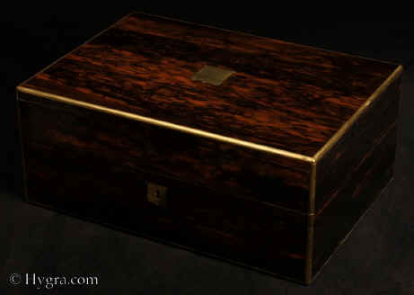 JB521: Antique box veneered in strongly figured coromandel, with brass edging and central inlaid brass plaque, and a working lever lock with key. The box is of high quality, which continues into the compartmentalized interior. It is lined in velvet and embossed leather. It has a lift-out tray. There is a document wallet in the lid. Circa 1850. Enlarge Picture