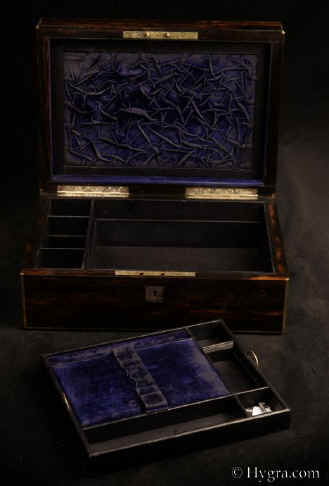 JB521: Antique box veneered in strongly figured coromandel, with brass edging and central inlaid brass plaque, and a working lever lock with key. The box is of high quality, which continues into the compartmentalized interior. It is lined in velvet and embossed leather. It has a lift-out tray. There is a document wallet in the lid. Circa 1850. Enlarge Picture