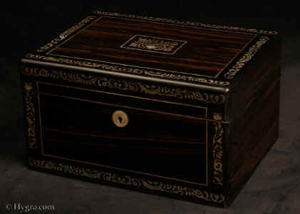 JB522: Antique figured coromandel box with rounded ebony edges, inlaid to the top and front with fine inlays of mother of pearl and white metal depicting stylized curved foliage. The box has a  sprung  drawer fitted for jewelry, and in the lid a document wallet.  Circa 1845. Enlarge Picture