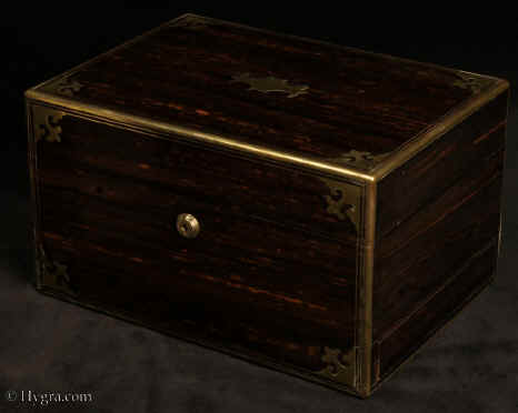 JB526:  Antique coromandel, brass-edged and accented box with secure Bramah lock: the box has a compartmentalized interior with leather covered lift out tray,  a button released drawer of dovetail construction fitted for jewelry,  with its own  hinged lid lined in padded silk. There is a mirror and document wallet in the lid.  Circa 1870. Enlarge Picture