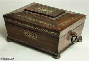 A  Rosewood box in the sarcophagus form.  The box is veneered in figured rosewood and is inlaid in brass depicting stylized flora. Enlarge Picture