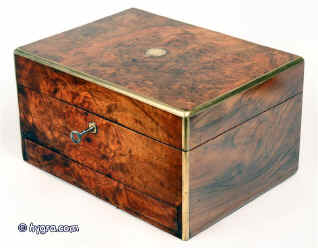 A burr walnut box with rounded brass edges having a liftout tray and spring released drawer suitable for jewelry by Fisher of the Strand, London; the box  is lined in velvet, silk and gold embossed leather and has a document wallet in the lid as well as a leather framed mirror. Enlarge Picture