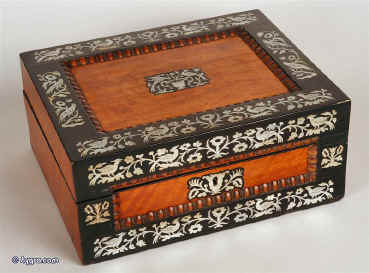 Antique box in satin-birch and ebony inlaid with mother of pearl depicting stylized birds and flora. The mother of pearl inlay is strongly executed and is finely engraved. The top and front of the box have fielded satin-birch panels framed by turned gadrooning in birch and ebony. Inside the box has been relined with hand made marbled paper. It has a velvet covered liftout tray. Working lock and key. Circa 1830 Enlarge Picture