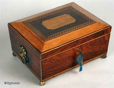 A shaped regency box in satin-birch and rosewood, the pyramided top having a central panel of birch and framed by a complex parquetry in birch and rosewood. The box retains its original gilded brass drop handles and ball feet. Inside the box is relined with hand made marble paper and has two later 19th c leather and velvet covered liftout trays fitted for jewelry. working lock and key circa 1830. Enlarge Picture