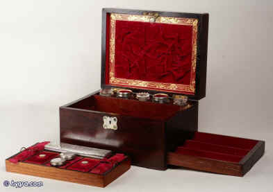 A rosewood veneered dressing box retaining its original cut crystal bottles with silver plated lids and lift-out tray with supplementary lids covered with embossed velvet. the box has a sprung side drawer of dovetail construction which is fitted for jewelry. There is a document wallet in the lid and a lift out mirror behind.  The document wallet is covered with ruched velvet and framed with gold embossed leather, circa 1840.  Enlarge Picture