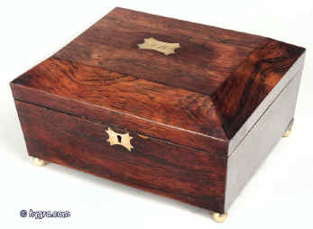 JB224: figured rosewood box with tapering tapering sides and  pyramid top, brass escutcheon and central top plate standing on brass ball feet. The box has its original yellow interior and liftout tray. There is a document wallet in the lid with  embossed leather framing and ruched yellow silk. Circa 1810. Enlarge Picture