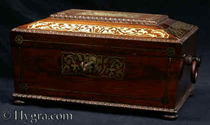 JB422: Antique  box in the sarcophagus form.  The box is veneered in figured rosewood and is inlaid in brass depicting stylized flora. The fluid design of stylised flora is exceptionally fine.  This is a spectacular box which encapsulates the best of the Regency era. The box stands on turned rosewood feet and has turned rosewood drop ring handles. The centre panel of the top is framed with gadrooning as is the pediment adding the architectural impact. The box has an added velvet lined tray. Circa1825. Enlarge Picture