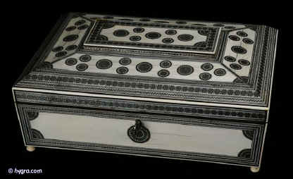SB403: Anglo Indian fully fitted sewing   box of pyramided shape veneered with ivory profusely inlaid with sadeli mosaic,  the box  standing on turned ivory feet. Inside the box is compartmentalized and fitted for sewing, with a liftout tray of  fragrant sandalwood and has supplementary lids and trays each veneered with ivory inlaid with sadeli,  circa 1845. Enlarge Picture