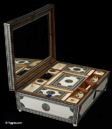 SB403: Anglo Indian fully fitted sewing   box of pyramided shape veneered with ivory profusely inlaid with sadeli mosaic,  the box  standing on turned ivory feet. Inside the box is compartmentalized and fitted for sewing, with a liftout tray of  fragrant sandalwood and has supplementary lids and trays each veneered with ivory inlaid with sadeli,  circa 1845.  Enlarge Picture