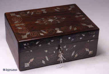 SB122: A rosewood veneered box, inlaid with mother of pearl and white metal in  a stylized pattern, which forms a fine foliated design in reverse having a lift out tray, still covered with its original printed pink paper  with divisions  for sewing.The workmanship is of high standard; for example, the box is edged with a rounded piece of wood which finishes it elegantly and also protects it.Circa 1835 Enlarge Picture