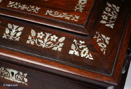 SB125: Antique  figured rosewood sewing box the top panel framed  inlaid with mother of pearl to the top and front having turned rosewood drop-ring handles and standing on  turned bun  feet. Inside the lid is lined with contrasting blue and cream silk and has a document wallet behind. The box has a liftout tray with supplementary lids covered in silk. Circa 1830.  Enlarge Picture