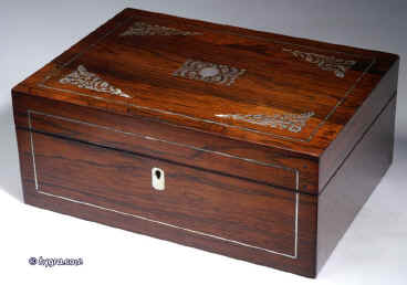 SB127:  A rosewood veneered box of rectangular form, inlaid with mother of pearl and white metal in  a stylized pattern, which forms a fine foliated design in reverse, the box having a lift out tray, still covered with its original blue paper  with divisions  for sewing.Circa 1830. Enlarge Picture