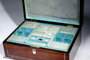 SB127:  A rosewood veneered box of rectangular form, inlaid with mother of pearl and white metal in  a stylized pattern, which forms a fine foliated design in reverse, the box having a lift out tray, still covered with its original blue paper  with divisions  for sewing.Circa 1830. Enlarge Picture