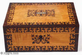 Sb451: Satinwood and rosewood veneered box with stylised floral design circa 1835. A beautifully elegant box. The composition contrasts the rich brown of the rosewood with the luminous sheen of the satinwood in stylized floral motifs, inspired both by earlier seaweed patterns and later neoclassical designs. The inlay is executed with impeccable precision and control and becomes an integral part of the whole structure of the box. The top central plaque is in mother of pearl and gives an extra punctuation to the composition. Small repairs to two of the corners on the top, seen when carefully examined. The tray is original and so is the blue paper and metal bead edging on the tray. The velvet covers are re-covered. Working lock and key. Enlarge Picture