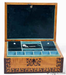 Sb451: Satinwood and rosewood veneered box with stylised floral design circa 1835. A beautifully elegant box. The composition contrasts the rich brown of the rosewood with the luminous sheen of the satinwood in stylized floral motifs, inspired both by earlier seaweed patterns and later neoclassical designs. The inlay is executed with impeccable precision and control and becomes an integral part of the whole structure of the box. The top central plaque is in mother of pearl and gives an extra punctuation to the composition. Small repairs to two of the corners on the top, seen when carefully examined. The tray is original and so is the blue paper and metal bead edging on the tray. The velvet covers are re-covered. Working lock and key. Enlarge Picture