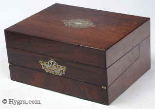 SB452: Rosewood veneered box with stylized brass and shell decoration circa 1870.
            This is an unusual box which combines a small writing box with a sewing tray. The engraved brass, mother-of-pearl and abalone decoration is fluid but
            stylized, combining the formality of neoclassicism with the naturalism of the Victorian era. The tray and the envelope compartment are original and hardly worn. The framing on the ruched surface is gold embossed. Working lock and key.   Enlarge Picture