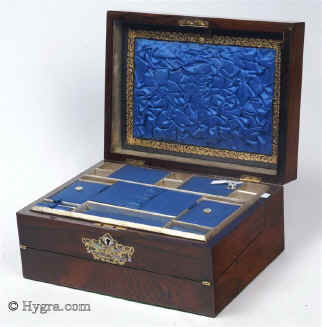 SB452: Rosewood veneered box with stylized brass and shell decoration circa 1870.
            This is an unusual box which combines a small writing box with a sewing tray. The engraved brass, mother-of-pearl and abalone decoration is fluid but
            stylized, combining the formality of neoclassicism with the naturalism of the Victorian era. The tray and the envelope compartment are original and hardly worn. The framing on the ruched surface is gold embossed. Working lock and key.    Enlarge Picture