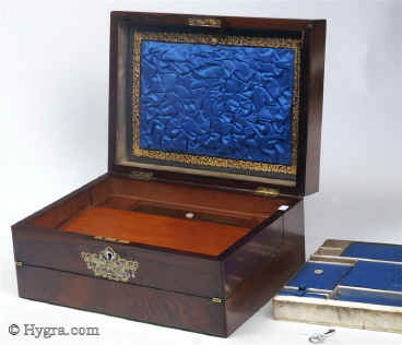 SB452: Rosewood veneered box with stylized brass and shell decoration circa 1870.
            This is an unusual box which combines a small writing box with a sewing tray. The engraved brass, mother-of-pearl and abalone decoration is fluid but
            stylized, combining the formality of neoclassicism with the naturalism of the Victorian era. The tray and the envelope compartment are original and hardly worn. The framing on the ruched surface is gold embossed. Working lock and key.    Enlarge Picture