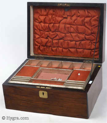 SB456: Walnut veneered box circa 1890. A sewing box veneered in walnut, its charm being its very simplicity. The central plaque an escutcheon are brass. The tray is original as is the ruched top and covers. The lighter
            coloured lining silk is later. The box has its own social history as it was given as a prize. Working lock and key.   Enlarge Picture