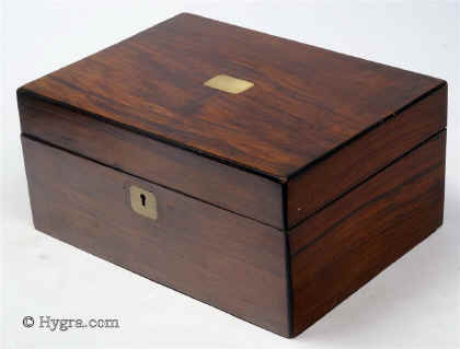 SB456: Walnut veneered box circa 1890. A sewing box veneered in walnut, its charm being its very simplicity. The central plaque an escutcheon are brass. The tray is original as is the ruched top and covers. The lighter
            coloured lining silk is later. The box has its own social history as it was given as a prize. Working lock and key.  Enlarge Picture