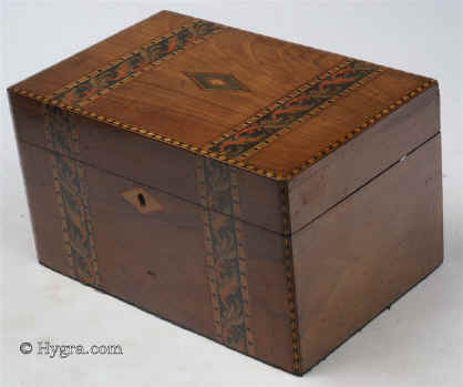 SB458: Walnut veneered box with leafy inlay circa 1880. This box is veneered in walnut and decorated with bands of micromosaic depicting leaves. This type of work, using stained wood, suggests Italian Sorrento work. The tray is probably a later addition and the box has been relined. Working lock and key. Circa 1880.   Enlarge Picture