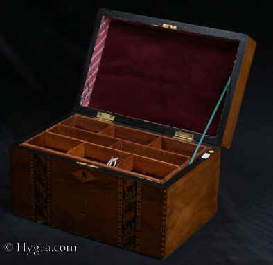 SB458: Walnut veneered box with leafy inlay circa 1880. This box is veneered in walnut and decorated with bands of micromosaic depicting leaves. This type of work, using stained wood, suggests Italian Sorrento work. The tray is probably a later addition and the box has been relined. Working lock and key. Circa 1880.    Enlarge Picture