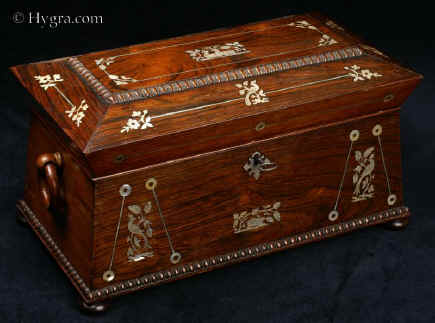 TC426:  Tea chest in highly figured rosewood of architectural form inlaid with mother of pearl which depicts stylized flora and fauna,  the chest standing on turned rosewood feet having turned drop handles. Inside the tea chest there are two liftout hinged canisters (retaining some of their original leading) and a particularly fine cut lead crystal bowl. Circa 1835-40. Enlarge Picture