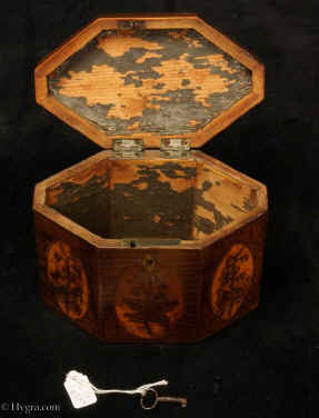 TC131: An Octagonal Caddy veneered in harewood having boxwood stringing and inlaid with
            oval marquetry panels depicting country flowers. Circa 1790.Enlarge Picture