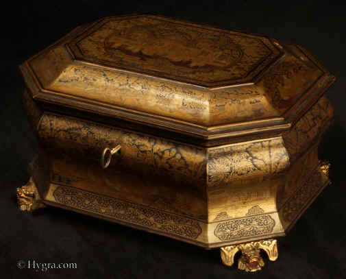 TC580:Large Chinese Export lacquer tea chest of elaborate shape decorated all over with gold of two colours depicting scenes of Oriental life depicting people in houses and gardens, opening to a single compartment containing two lidded pewter tea canisters with supplementary inner lids, the whole chest standing on feet in the form of dragon heads.  Circa 1840. Enlarge Picture