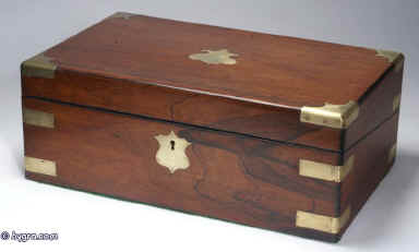 WB167: Figured rosewood writing box with brass corners and straps escutcheon and plate opening to an embossed leather (replacement) writing surface and compartments for writing implements and paper, and having two secret drawers concealed behind a sprung panel. The box has two hand blown replacement reproduction inkwells. Circa 1840 Enlarge Picture