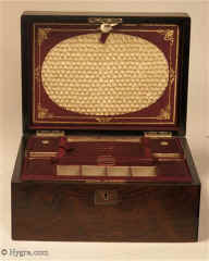Ref: 637SB: Fitted figured rosewood sewing box with lift-out tray. The box is in very good original condition. There is a document wallet in the lid.  The front of the document wallet is covered with ruched  satin silk and framed by wine colored silk with gilded embossing. The tray retains its original supplementary lids with places designed to hold sewing tools. Circa 1850.   Enlarge Picture