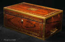 Regency brass bound writing box in highly figured rosewood with further brass inlay in the manner of the Royal cabinet-maker George Bullock, with counter sunk side carrying  handles, Bramah type lock with key, secret drawers,  and further large side drawer. The box retains its original gold embossed leather writing surface, inkwell and pounce pot, circa 1820.-Enlarge Picture