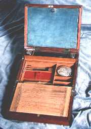 A combined writing box and dressing box of c1800. The top writing flap opens down to give access to grooming/shaving accessories. The lower flap has the conventional space for storing paper. The box is typical of the period made with solid mahogany reinforced with brass bindings. The brass binding protects the box from warping in changes of humidity. It also provides structural reinforcement for something expected to have a hard and useful life.         