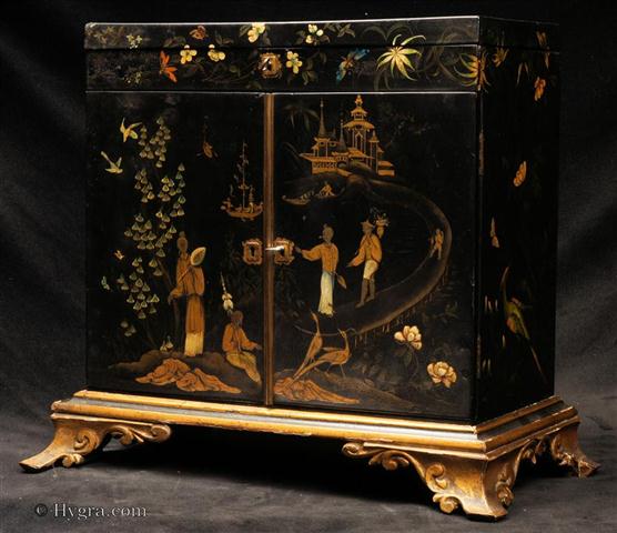 Rare 18th C painted Papier Mch table cabinet on gilded carved wooden stand. The two door cabinet with hinged top is decorated with chinoiserie themes on the outside and inside with wild flowers and butterflies. Enlarge Picture